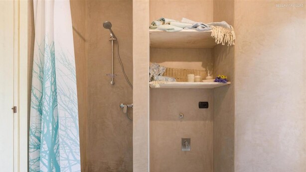 Ein Badezimmer mit Dusche, Handtuchhalter und Ablage für Toilettenartikel.