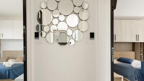 A modern hotel room with a wall-mounted mirror arrangement, a bed with blue bedding, and a wooden floor. - 1284 B B Dreams and Delights - Comfort Camera Tripla (Porto Cesareo)