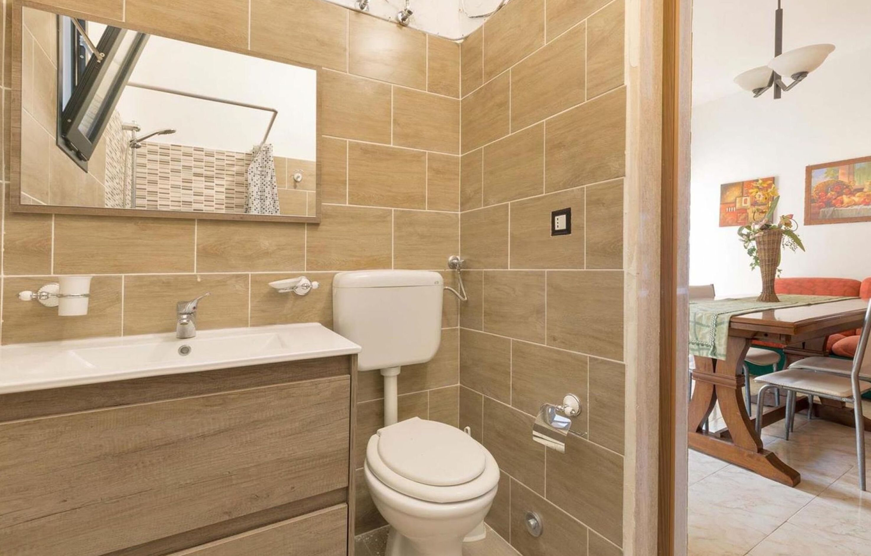 A bathroom with a sink, toilet, and mirror.