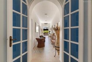 A corridor with white walls and blue-framed windows, leading to a garden area. - 2148 Villa Giusy in Mancaversa (Taviano)