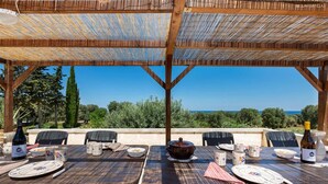 Un espacio de comedor al aire libre con mesas, sillas y vista al mar.