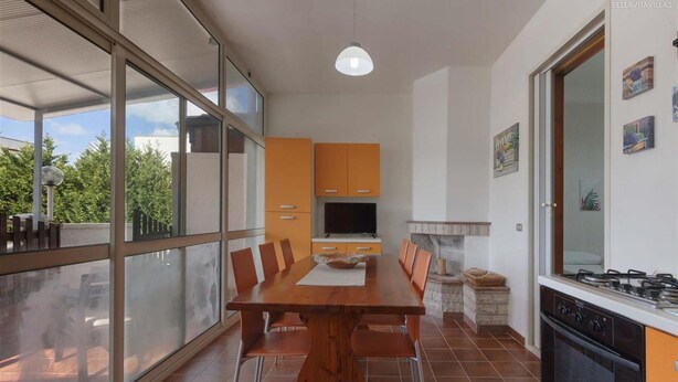 Una cocina moderna con comedor, ventanas amplias y televisor.