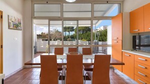 Una cocina moderna con gabinetes naranja, una mesa de comedor con sillas y un ventanal con vistas a un jardín.