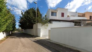 Una calle estrecha con un edificio blanco, un árbol y un cielo despejado.