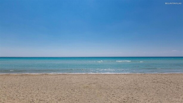 A beach with clear blue water and a sandy shore.