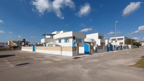 A modern building with a white facade, blue accents, and a no parking sign.