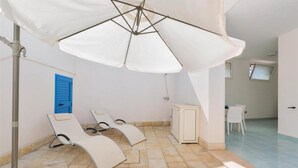A sunlit room with a ceiling fan, a blue window shutter, and a white table.