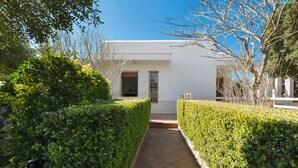 A pathway flanked by neatly trimmed hedges leading to a building with a white facade and a visible entrance. - 843 Serra Degli Angeli (Porto Cesareo)