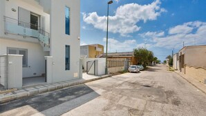 A residential street with modern houses, a clear sky, and parked cars. - 1064 PMR - Appartamento Dei Delfini (Porto Cesareo)