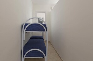 A narrow hallway with two bunk beds, a door at the end, and a white wall.
