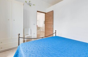 Ein Schlafzimmer mit einem Bett, einem Kleiderschrank, einer Tür und einem Stuhl.