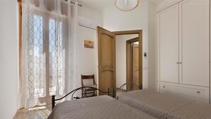 Ein Schlafzimmer mit zwei Betten, einer Holztür, einem Stuhl und einem Kleiderschrank.