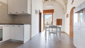 Eine moderne Küche mit weißen Schränken, einer gefliesten Spritzschutzwand und einem Essbereich mit Tisch und Stühlen.
