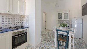 Cocina compacta con armarios blancos, cocina a gas, horno y refrigerador.