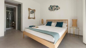 A bedroom with a wooden bed, a bedside table, a wall-mounted mirror, and a decorative wall piece. - 1738 Tenuta Degli Ulivi (Melendugno)