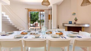 A dining area with a white table set for six, a staircase, and a view of the outdoors. - 2064 Villa Stella Blu by Barbarhouse (Manduria)