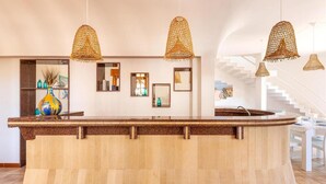 A modern kitchen with a curved island, hanging wicker pendant lights, and a staircase leading to an upper level. - 2064 Villa Stella Blu by Barbarhouse (Manduria)