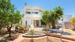 A two-story house with a balcony, a paved patio, and a garden area with trees and plants. - 2064 Villa Stella Blu by Barbarhouse (Manduria)