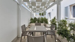 Eine Terrassengruppe mit Tisch und Stühlen, umgeben von Blumentöpfen und einem Pergolenbau.