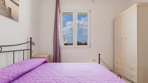 Ein Schlafzimmer mit Bett, Kleiderschrank, Fenster und Nachttisch.