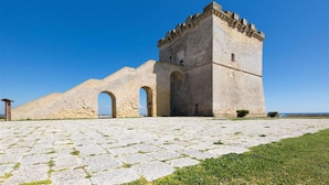 Ein historisches Steinhaus mit einem Turm, einem Bogenportal und einem gepflasterten Innenhof.
