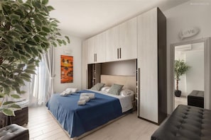 Una camera da letto moderna con un letto, un armadio, una panca e una pianta in vaso.