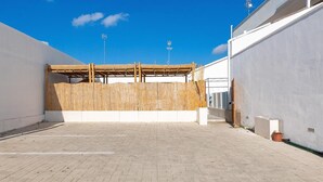 A courtyard with a bamboo fence, a covered area, and a paved walkway.