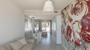 A modern interior with a sofa, a glass shower enclosure, and a large abstract painting.