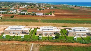 A modern residential complex with multiple houses, green lawns, and a view of the sea.