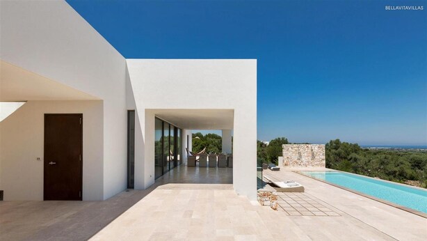 Eine moderne Villa mit Swimmingpool, überdachter Terrasse und Blick auf die Landschaft.