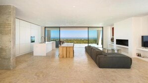 Ein modernes Interieur mit Küche, Essbereich und Wohnzimmer, mit einem großen Fenster mit Blick auf eine Landschaft.
