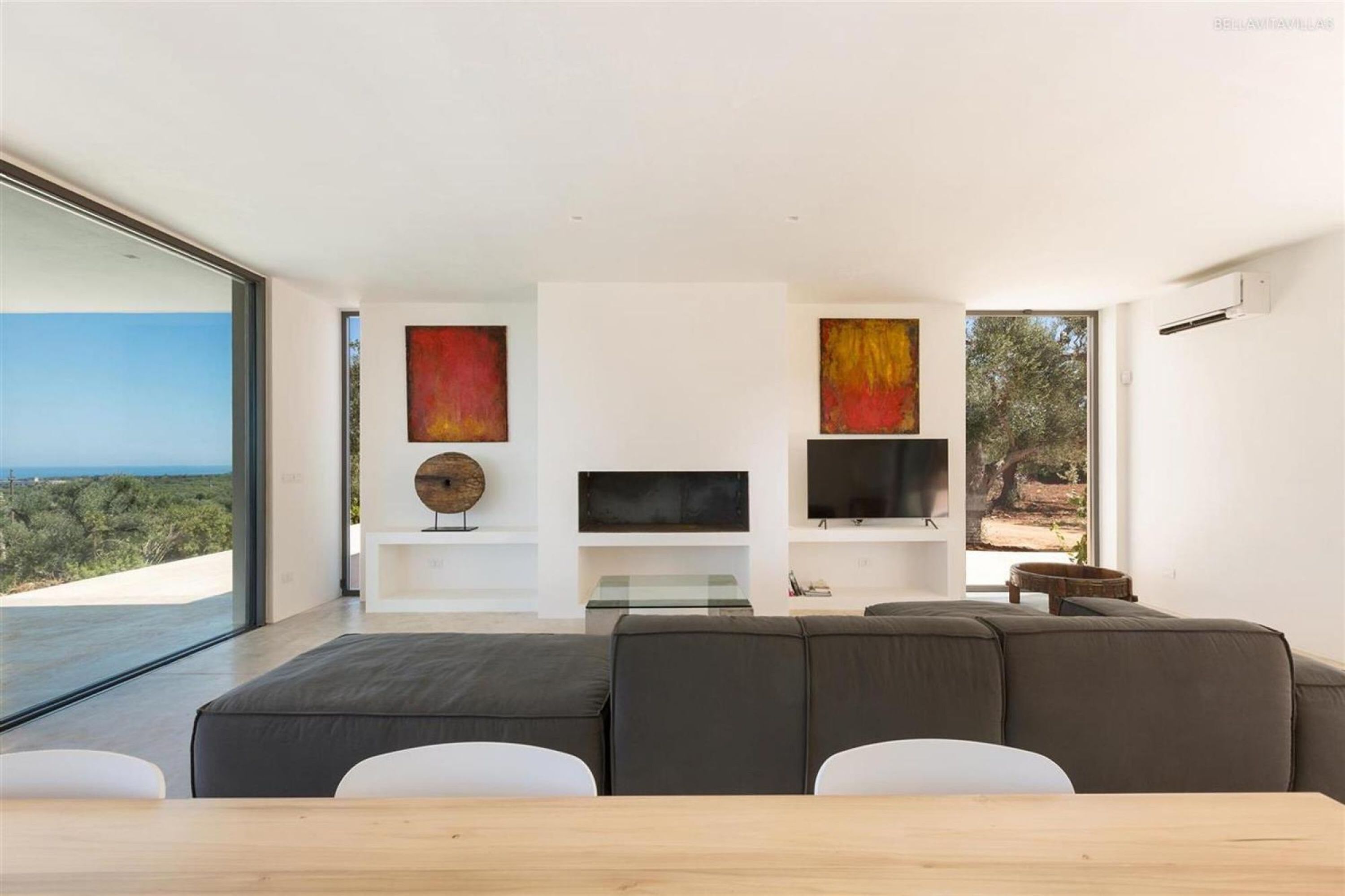 A modern living room with a large sofa, a flat-screen TV, and artwork on the walls.