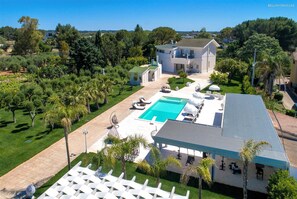Una amplia casa con piscina, mobiliario exterior y un patio cubierto.