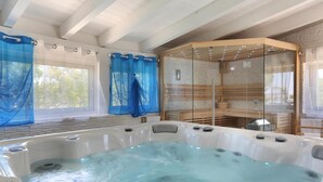 Een wellnessruimte met een jacuzzi, een douchecabine van glas en houten banken.
