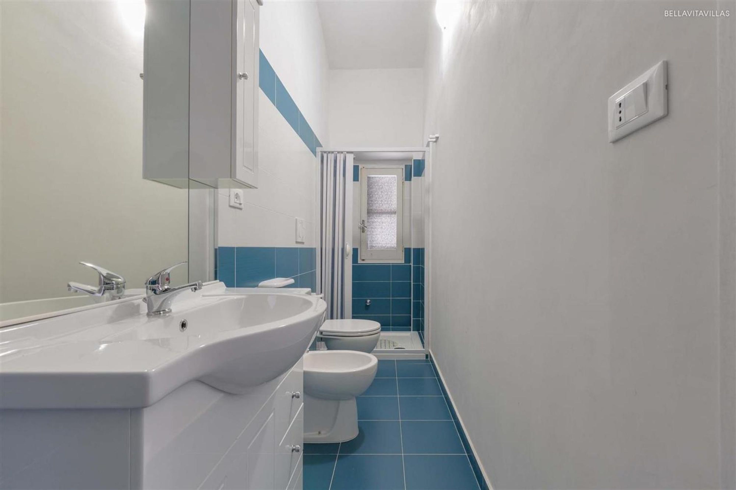 Ein modernes Badezimmer mit einem großen Waschbecken, zwei Toiletten und einer Dusche.
