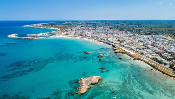 An aerial view of a coastal town with a clear blue sea, a sandy beach, and a rocky outcrop. - 2191 Appartamento Blue Dreams by Barbarhouse (Melendugno)