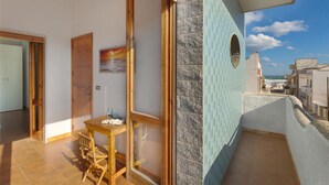 A room with a wooden table, a chair, a door, and a view of the sea. - 2191 Appartamento Blue Dreams by Barbarhouse (Melendugno)