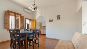 A dining area with a wooden table and chairs, a sofa, and a kitchen in the background. - 2191 Appartamento Blue Dreams by Barbarhouse (Melendugno)