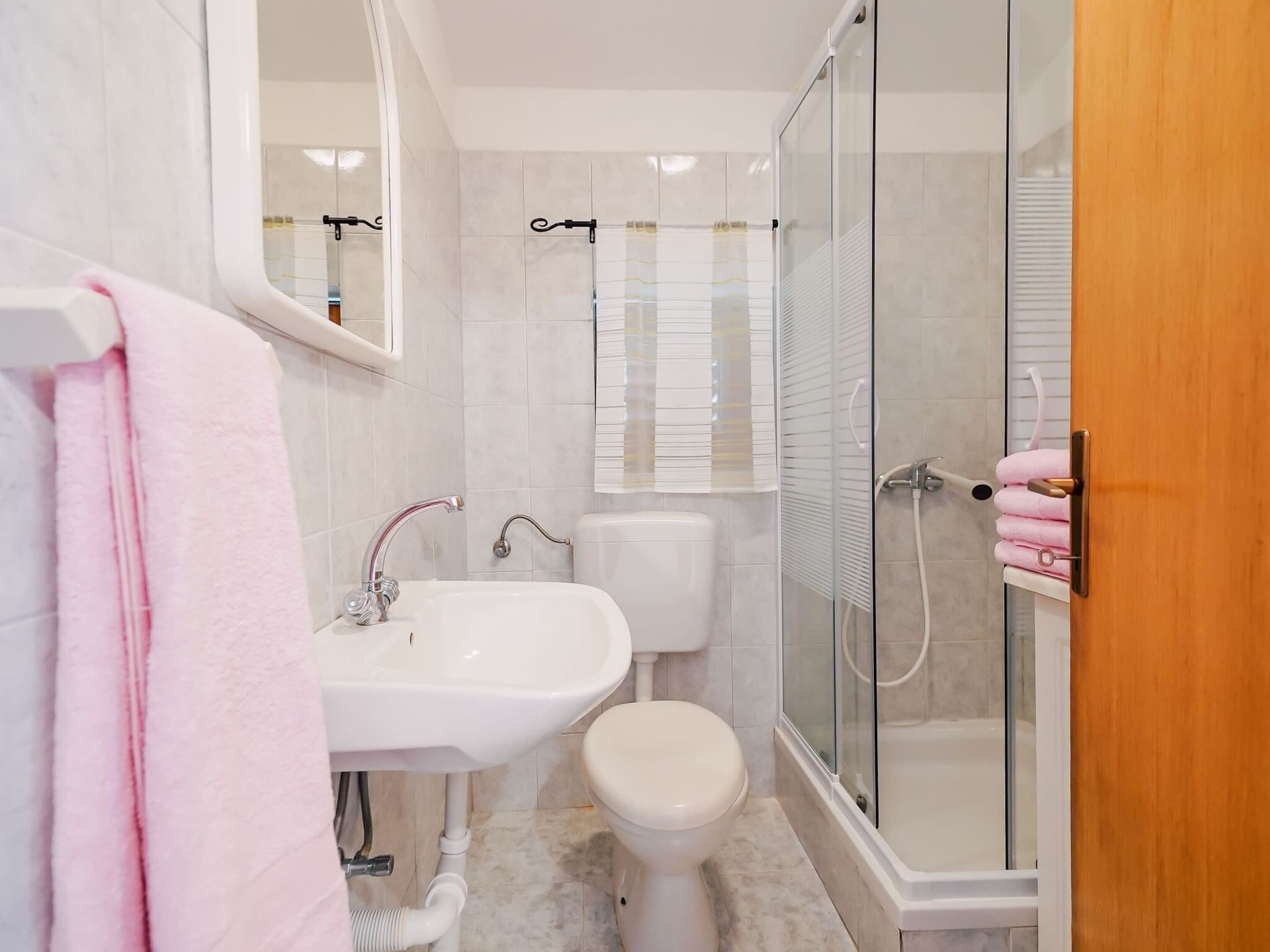 A bathroom with a sink, toilet, and glass-enclosed shower.