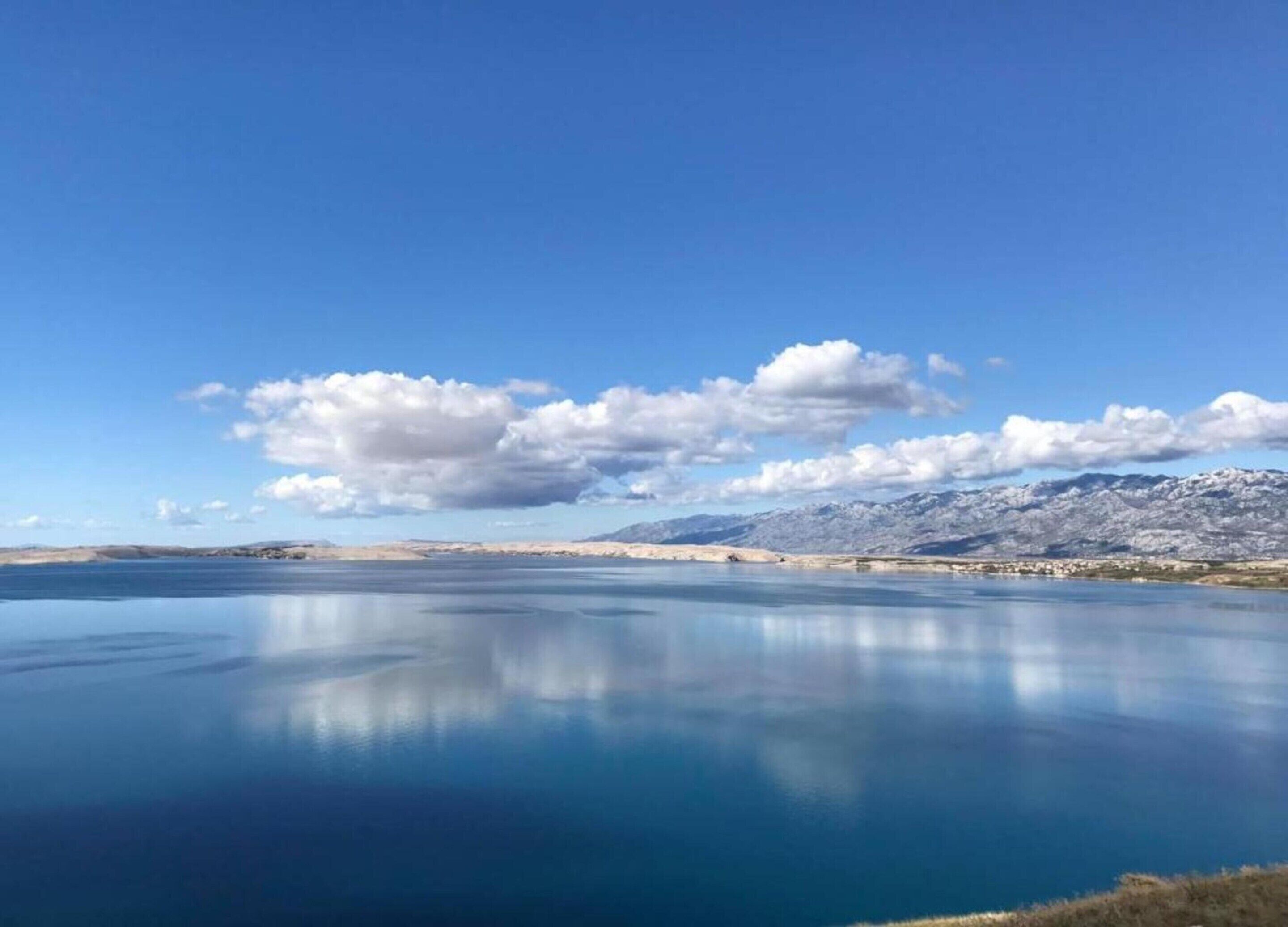 A calm lake with mountains in the background and a clear sky.