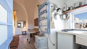 A compact kitchen with a white refrigerator, a small stove, and a blue shelf unit holding various kitchenware. - 574 Loft nel Centro Storico di Presicce (Presicce-Acquarica)