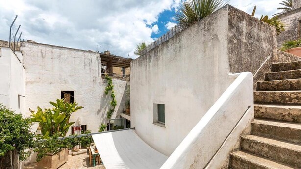 A courtyard with a white ramp leading to a staircase, surrounded by buildings and greenery. - 574 Loft nel Centro Storico di Presicce (Presicce-Acquarica)