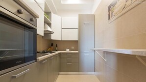 Une cuisine moderne dotée d’un four encastré, de meubles en acier inoxydable et d’un plan de travail blanc.