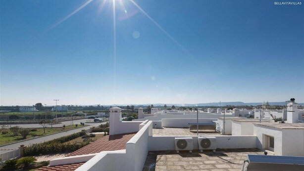 Une terrasse sur le toit offrant une vue dégagée sur le paysage environnant, notamment sur une route et des collines lointaines.