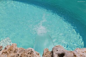 On aperçoit clairement une piscine, et on distingue des formations rocheuses au fond.