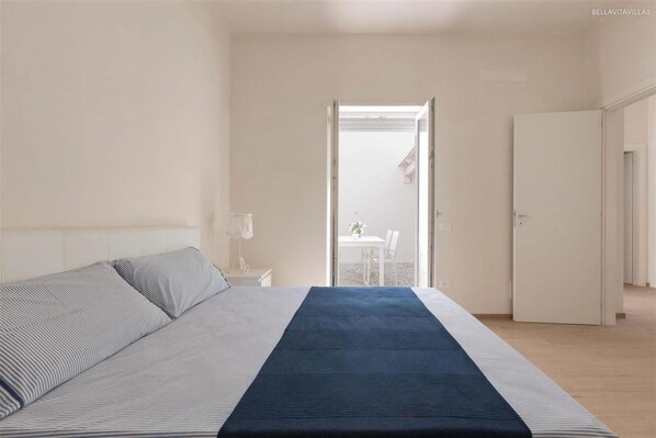 A bedroom with a bed, a nightstand, and a view of a balcony. - 1201 Villa Adele in Maruggio (Maruggio)