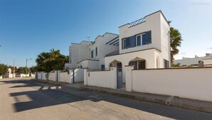 Un edificio moderno con facciata bianca e persiane blu, dotato di cancello e cielo sereno.