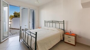 Camera da letto con un letto, un comodino e una porta scorrevole in vetro che dà su un patio.