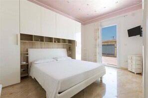 A bedroom with a bed, built-in shelving, a television, and a sliding glass door to the outside. - 1695 Villa Albarosa in Ruffano (Ruffano)