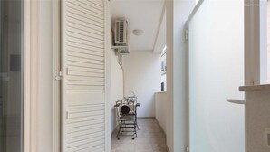 A narrow hallway with a sliding door, an air conditioning unit mounted on the wall, and a metal chair in the center. - 2200 Al Castello Home Holidays - Bilo by Barbarhouse (Otranto)